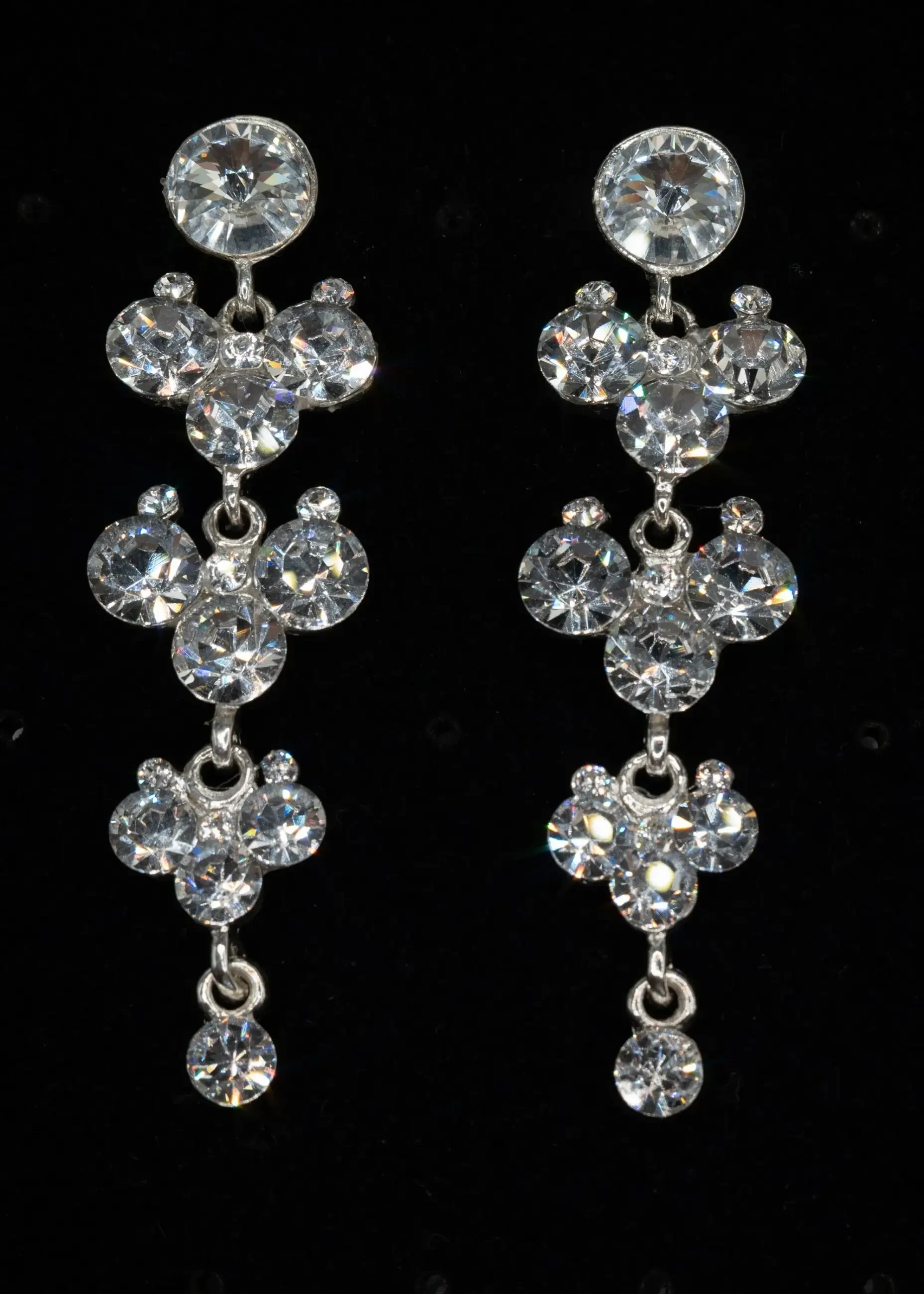 Elegant crystal drop earrings with multiple shimmering stones are displayed against a black background, exuding a sophisticated and glamorous tone.