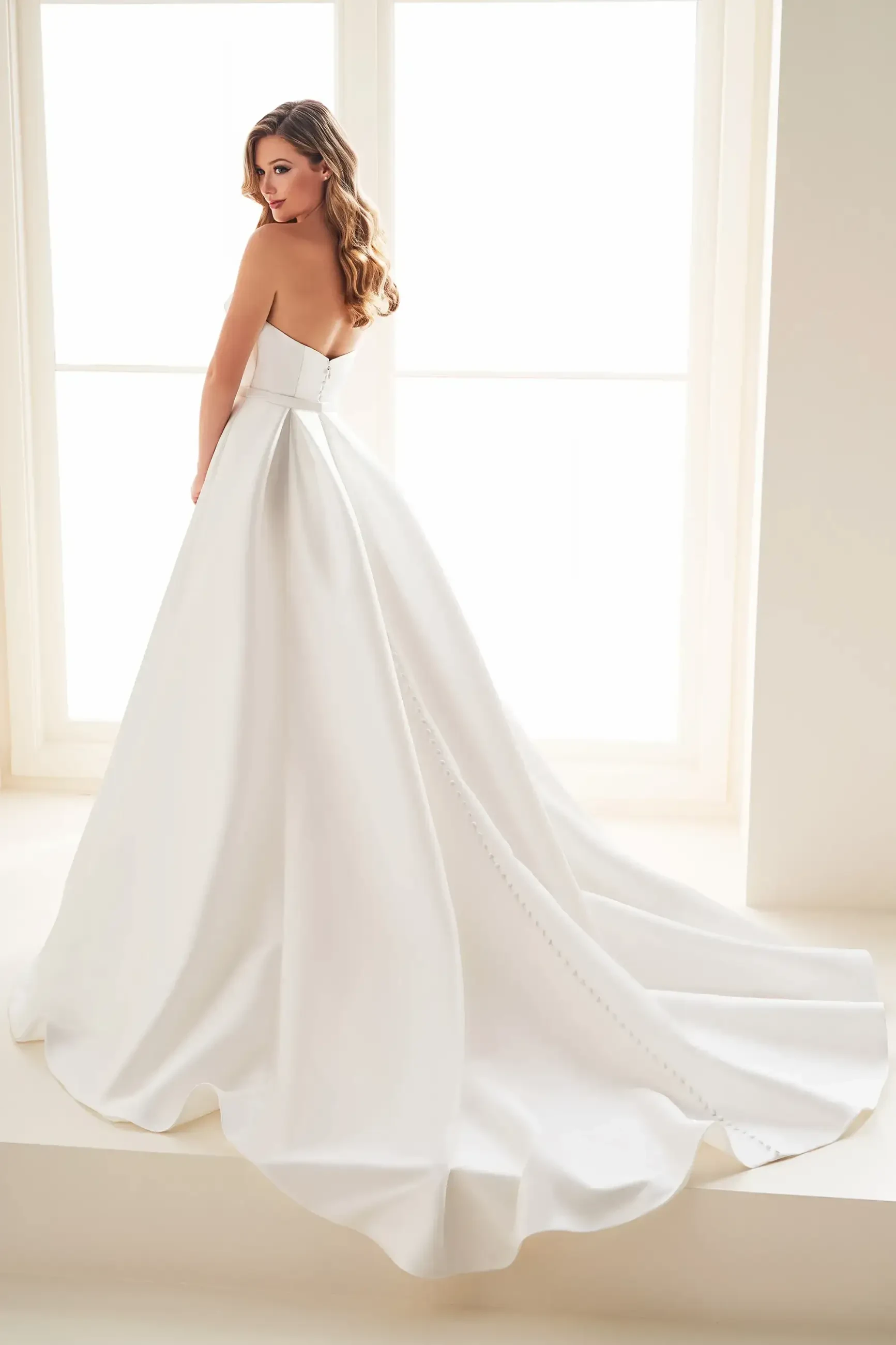 model is wearing a strapless ball gown wedding dress in diamond white