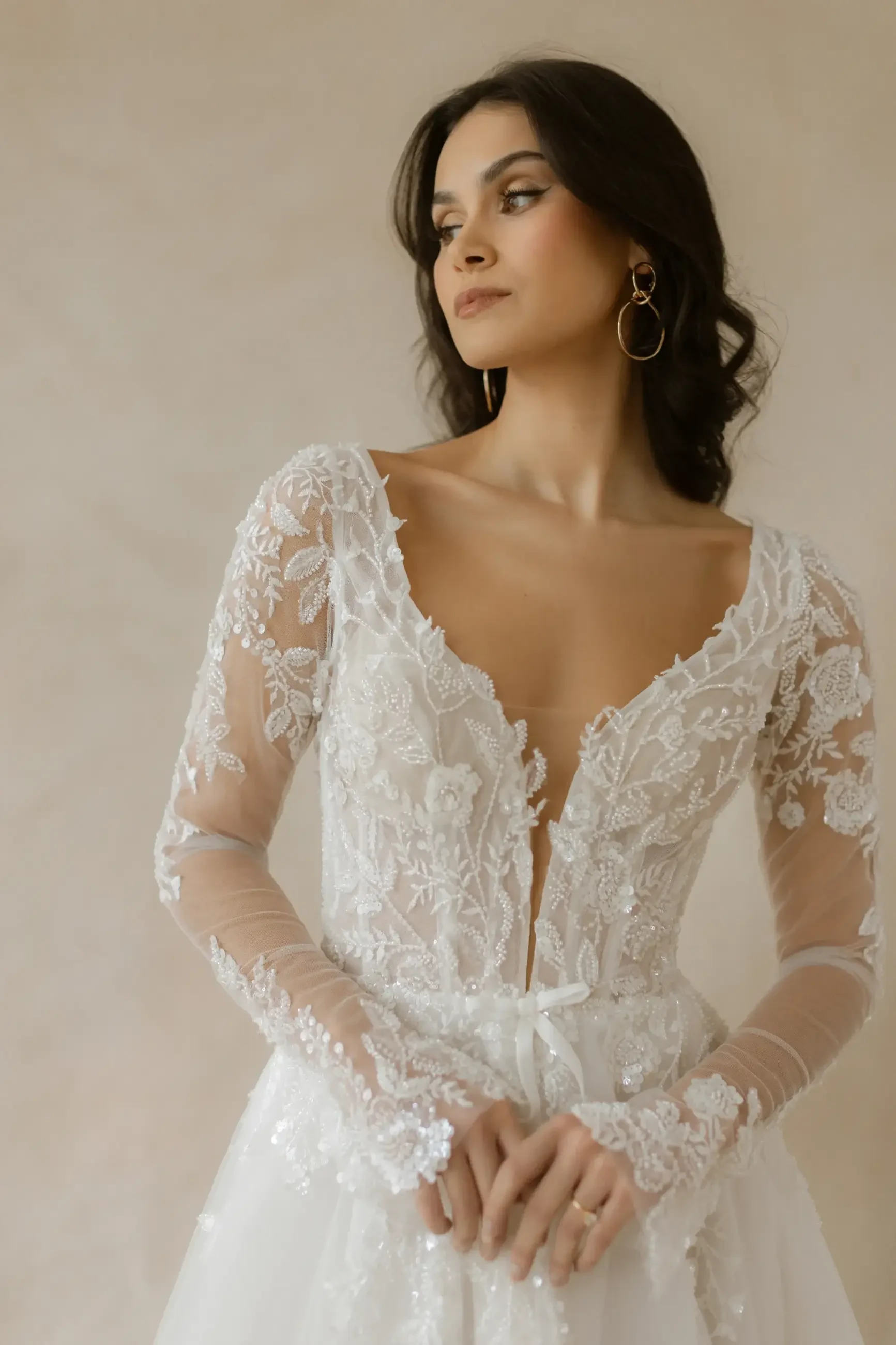 model is wearing a long sleeve lace bridal gown