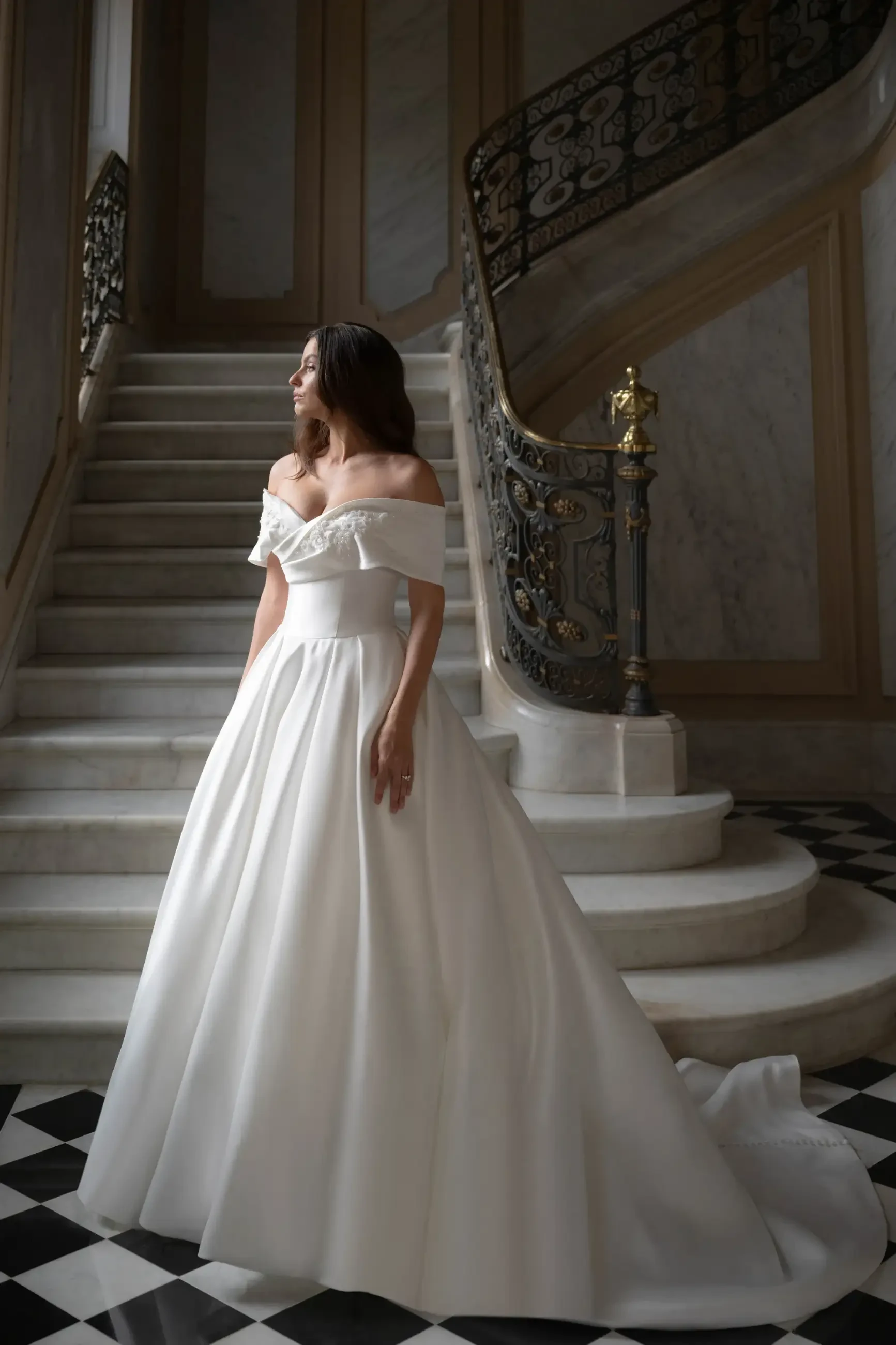 model is wearing an off the shoulder ball gown wedding dress