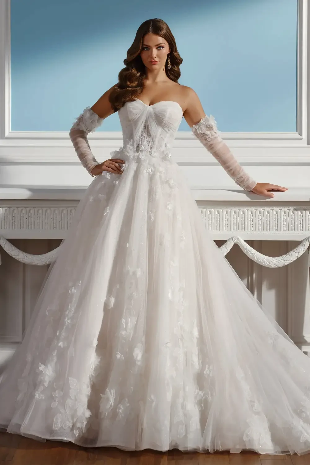 A woman in a strapless, white ball gown adorned with floral patterns, standing elegantly with her hands resting on a white table.
