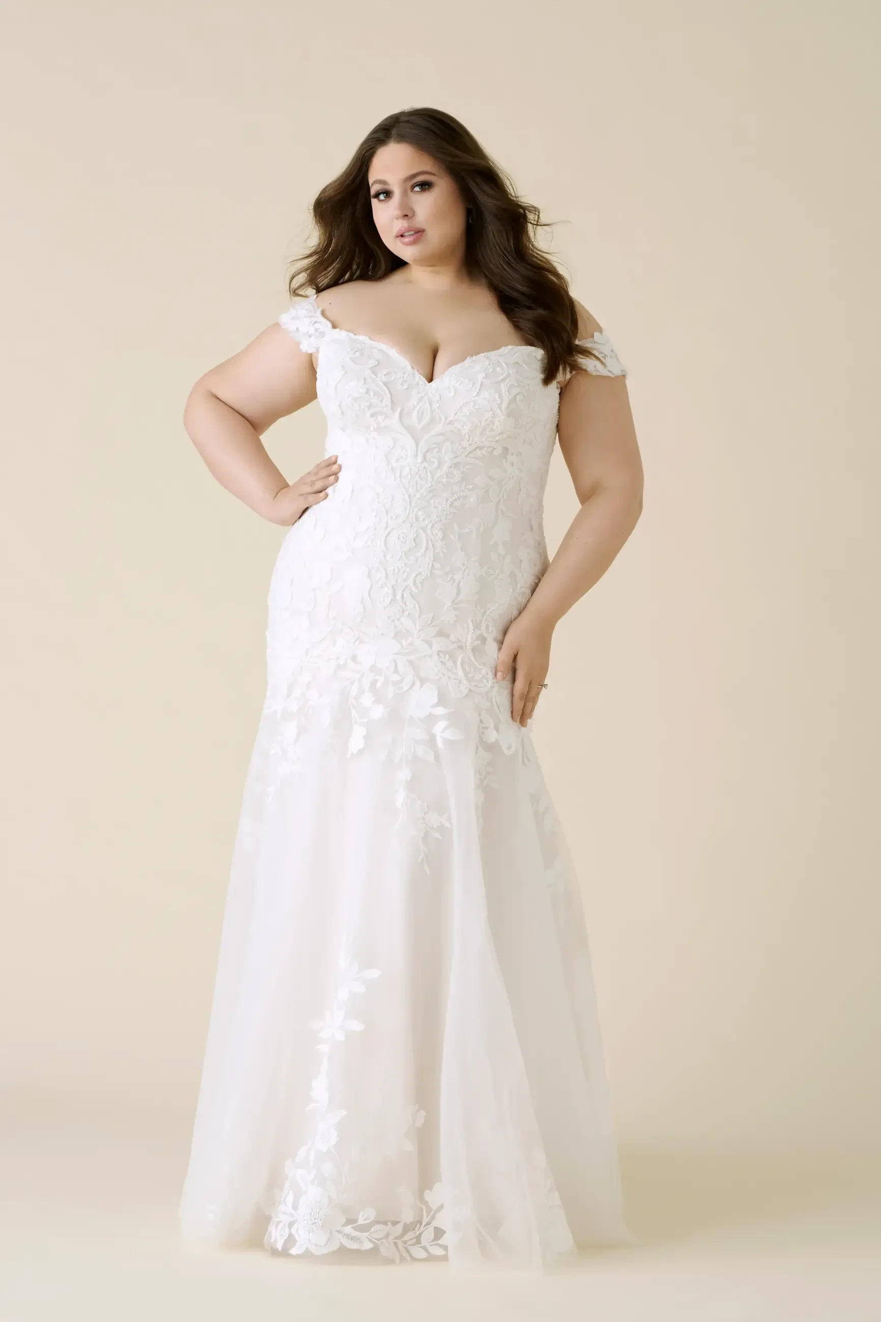 model is wearing an off the shoulder lace fit and flare bridal gown