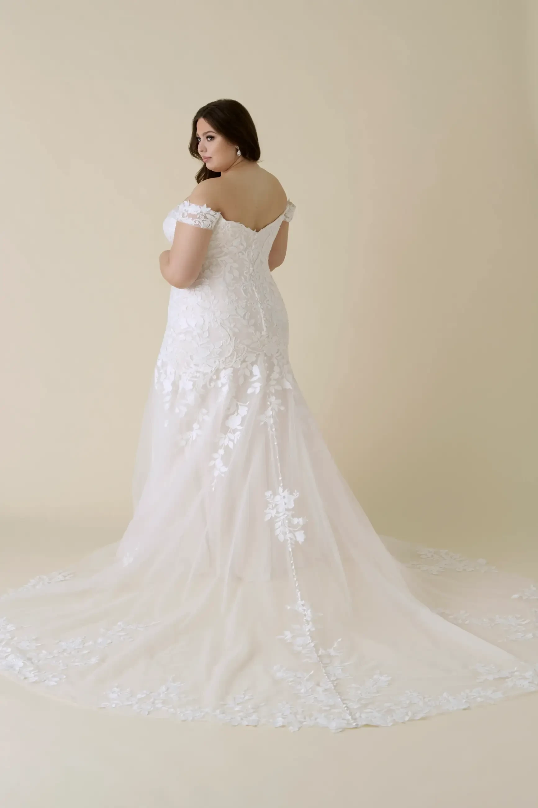 model is wearing an off the shoulder lace fit and flare bridal gown