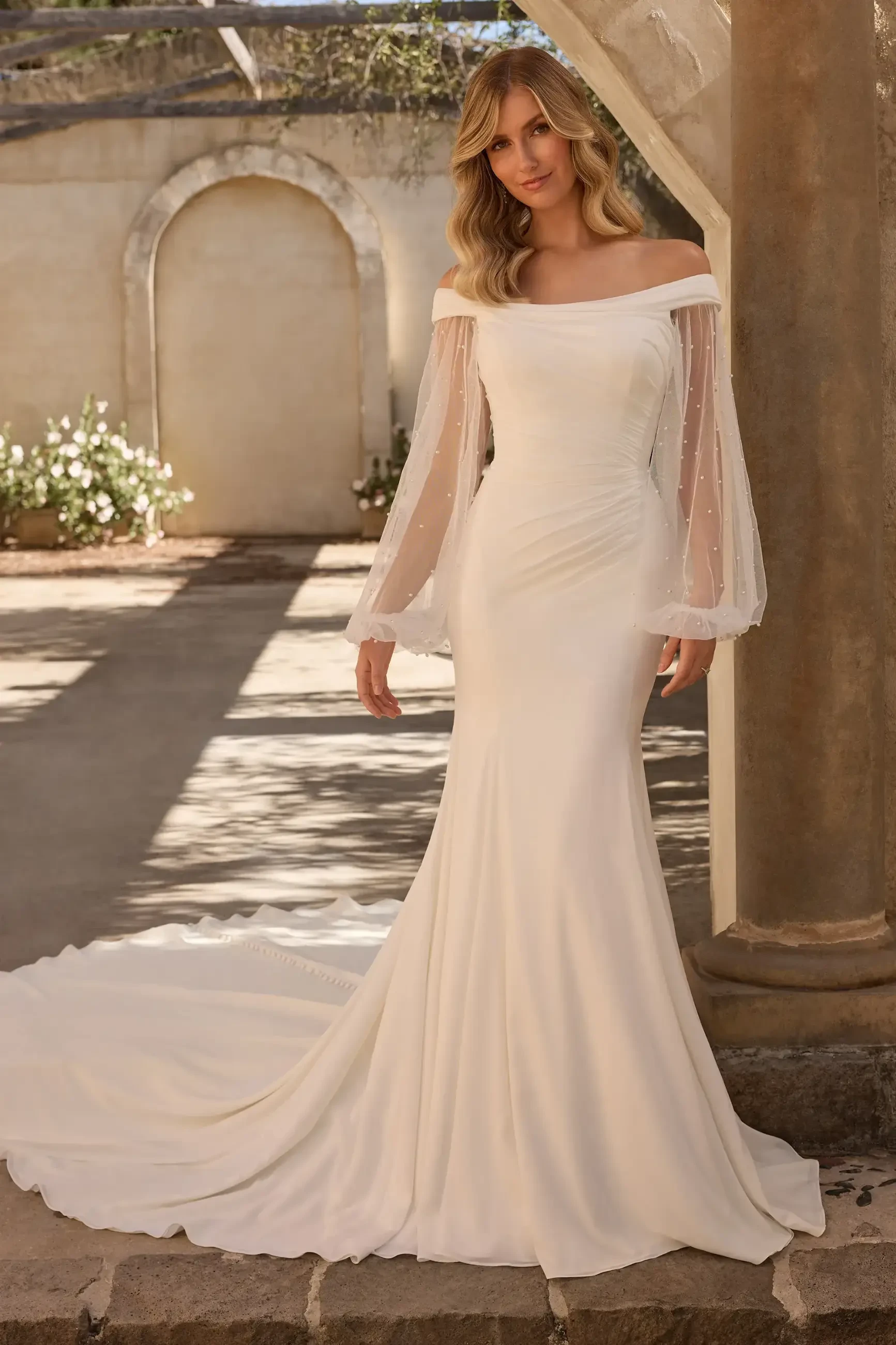 model is wearing a long sleeve wedding dress with pearls
